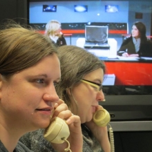 Phone workers in Hour 3 field answers while UTVS hosts television coverage in the background.