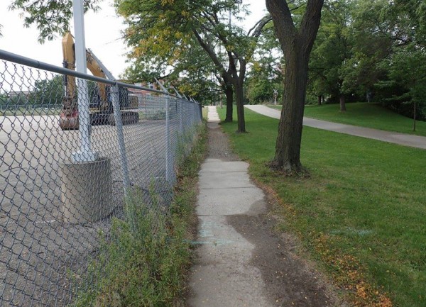 The light blue spray painted line on the path marks a sewer line that runs from the site to a open grate in the grass to the right. Residents are very concerned about contaminated site runoff with Yahara river so close by. Courtesy: FB/DOA Demolition